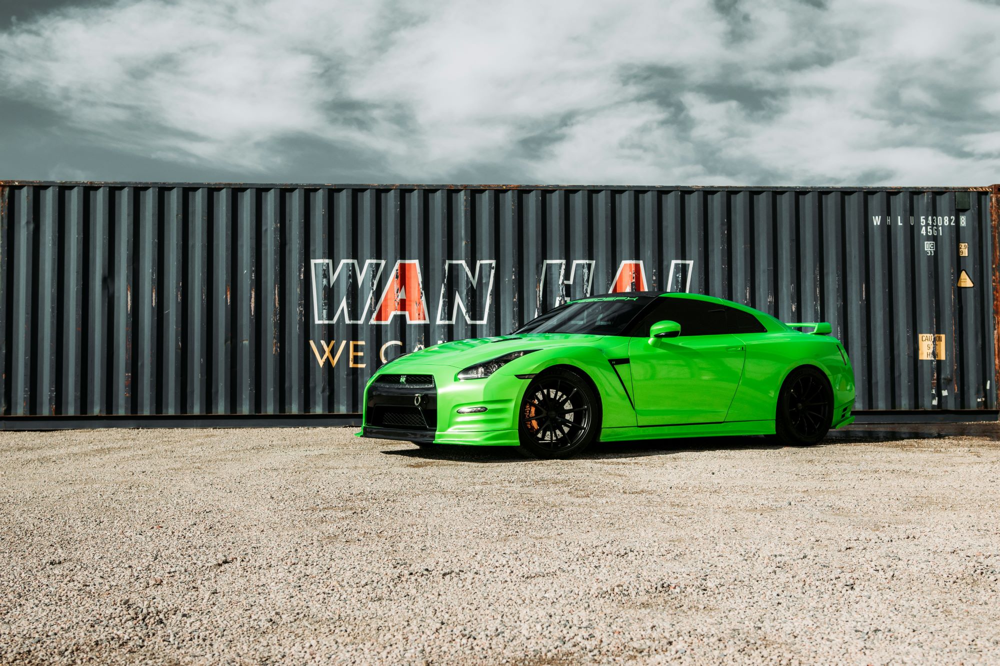 Green Nissan Skyline parked in front of a shipping container. How much does importing a car from Japan cost?