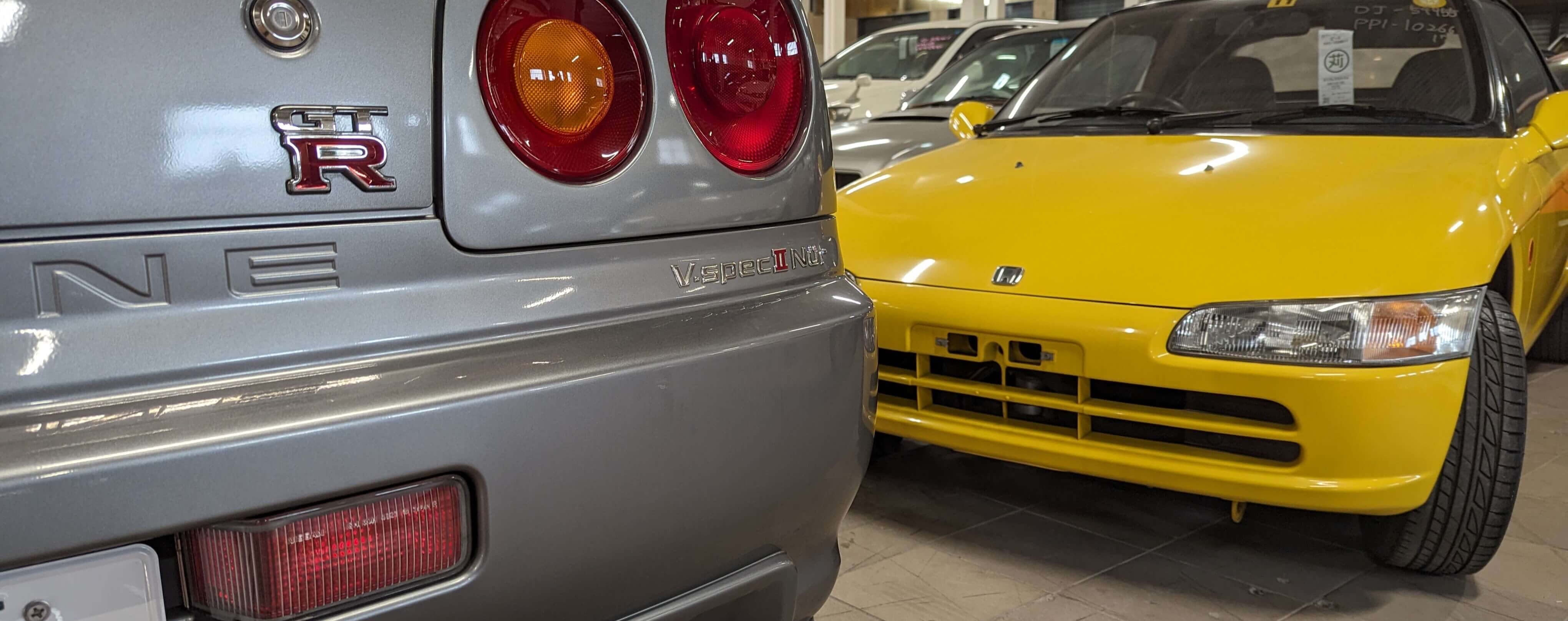 A Nissan Skyline GT-R V-Spec II Nur and a Yellow Honda Beat